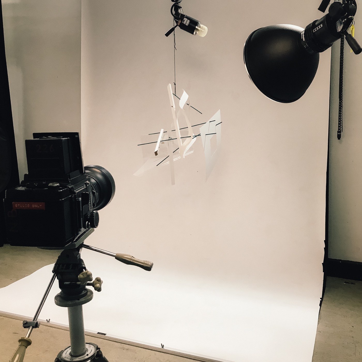 Studio process: a camera and lights aimed at a suspended paper sculpture