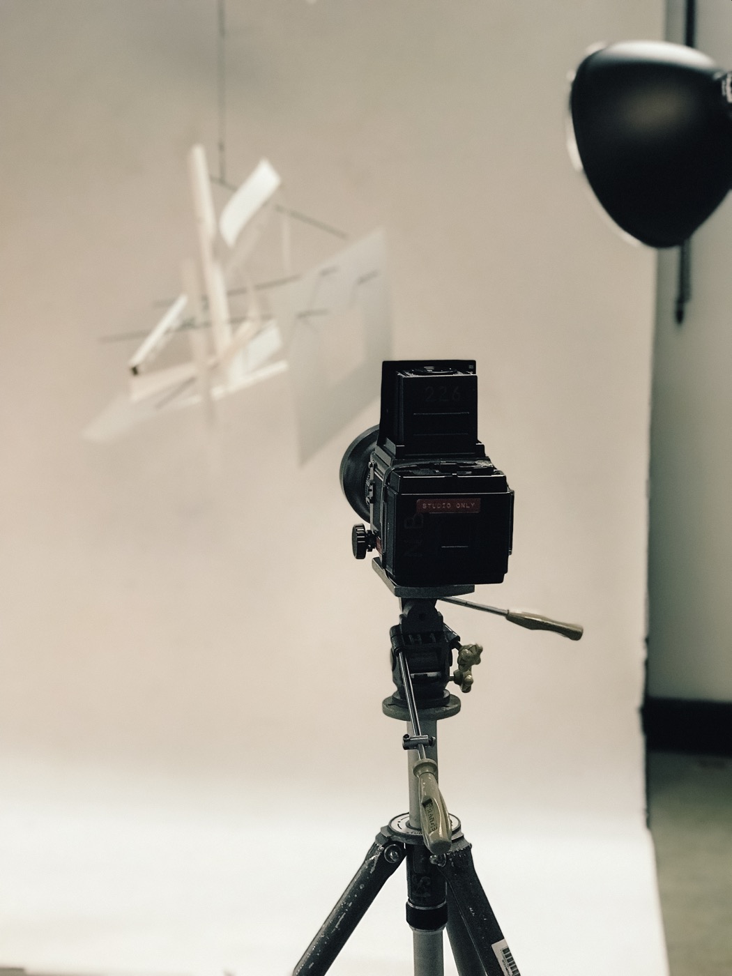 A large-format camera on a tripod facing a constructed studio setup