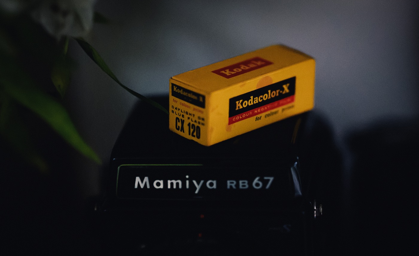 A dark, moody analogue still life with a medium-format camera and film box