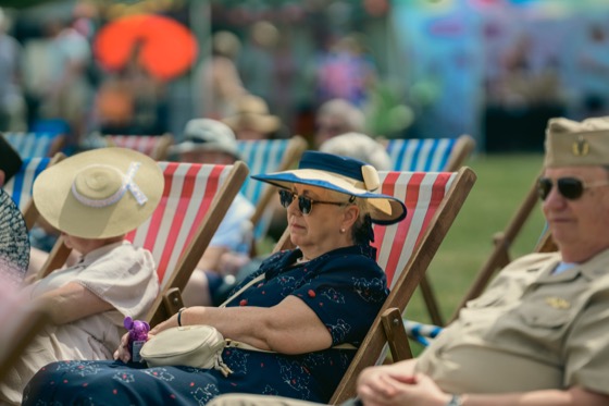 A woman in a blue hat sitting in a deckchair among other spectators.