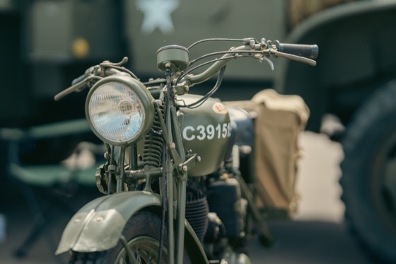 A BSA military-style motorcycle displayed beside other vintage vehicles.
