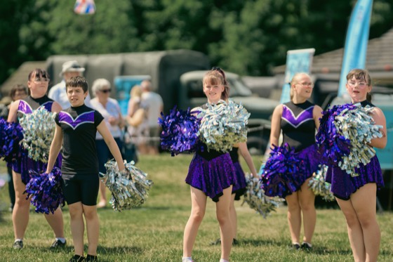 A youth dance group performing with pom-poms at an outdoor public event.