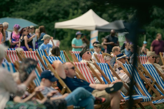 A crowd sitting in striped deckchairs at a 1940s themed outdoor event.
