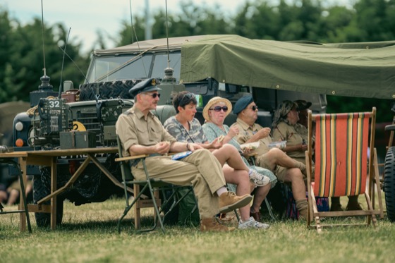 People sitting in folding chairs beside a military-style vehicle during a 1940s themed event in Sleaford.