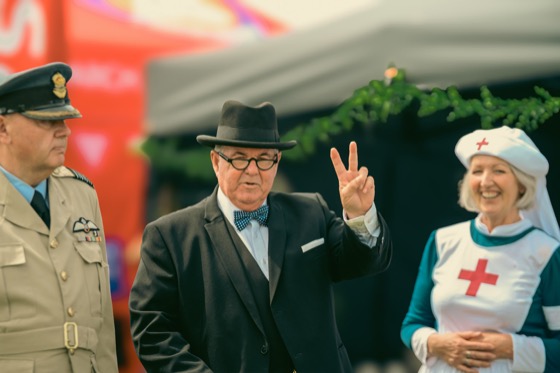 A costumed group at a 1940s themed event, with one man making a V sign.