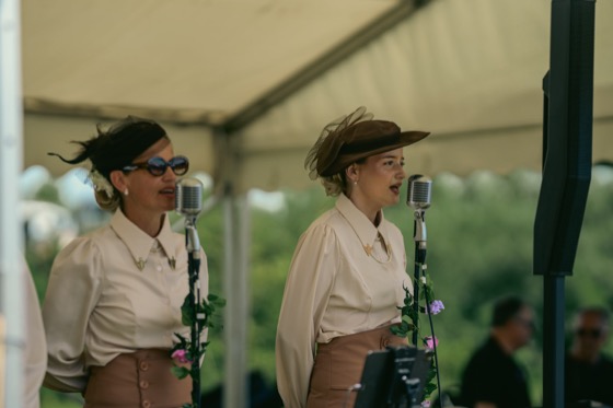 Two women singing into vintage-style microphones at a 1940s themed event.