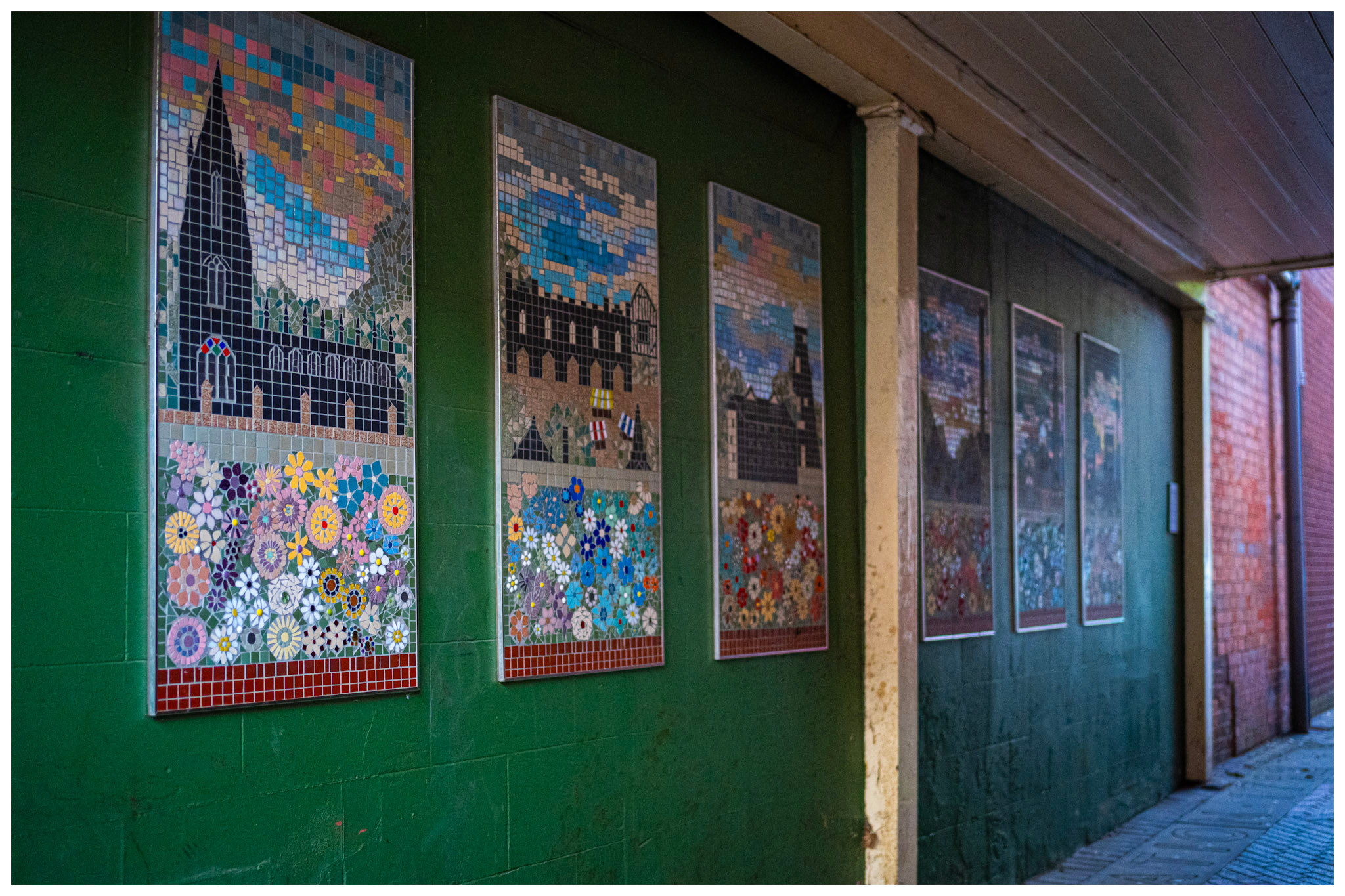 Six colourful mosaic panels of Sleaford buildings and flowers line the green entrance wall to Gladstone's Yard.
