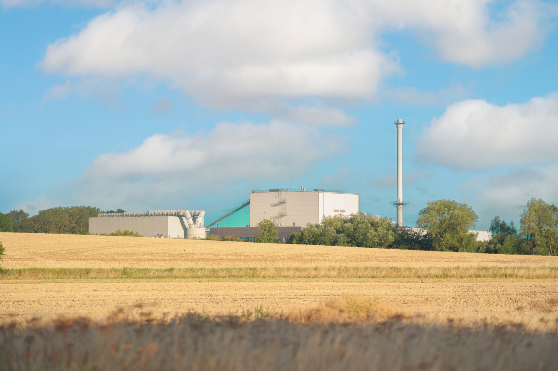 A working industrial building and chimney seen across a harvested field at Sleaford's edge.