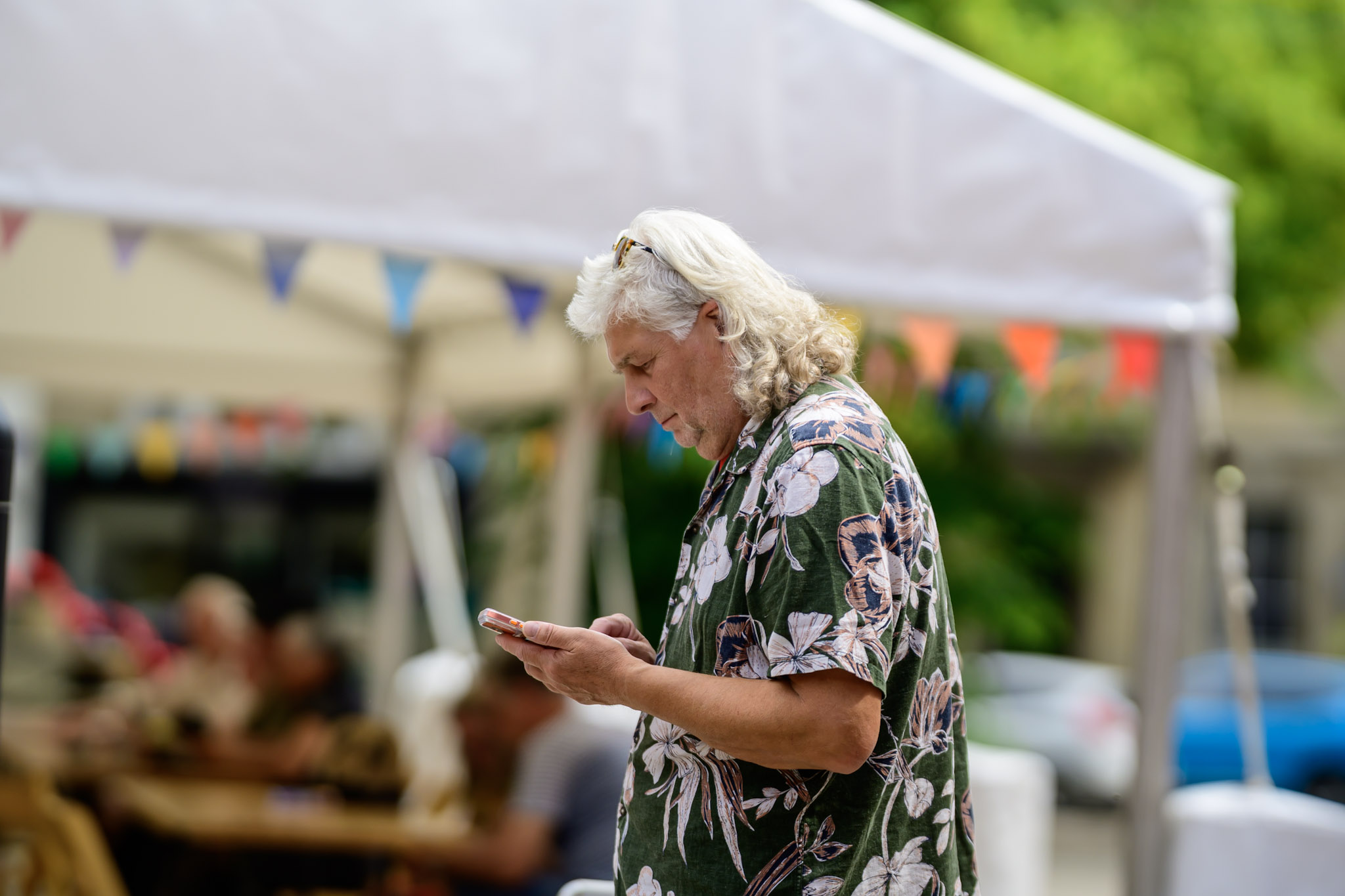 Festival visitor looking at a phone under a canopy