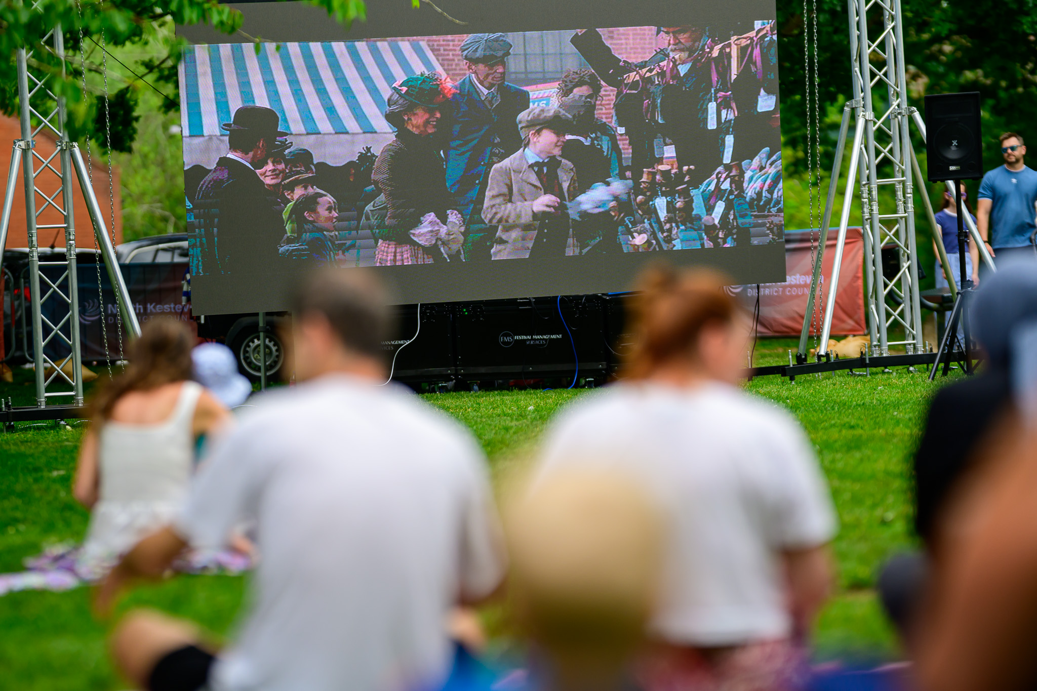 People sitting on grass watching a large screen at Sleaford Midsummer Festival